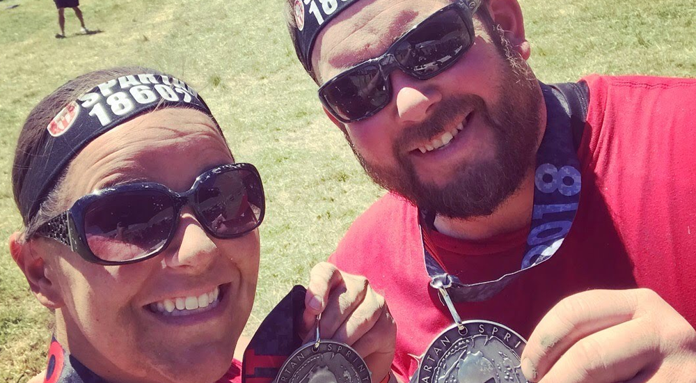 Stephanie Holt and her husband smiling with their Spartan Race medals