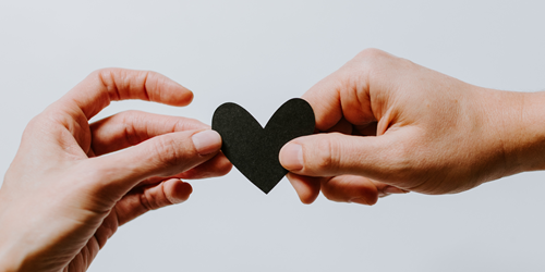 two hands holding a construction paper heart