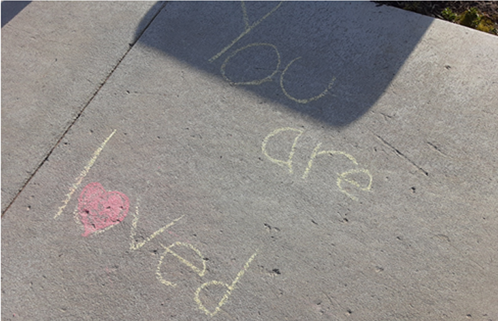 Chalk design on sidewalk that says "You are loved"