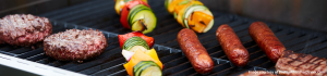hamburgers, hot dogs, and vegetable kabobs on an open BBQ grill